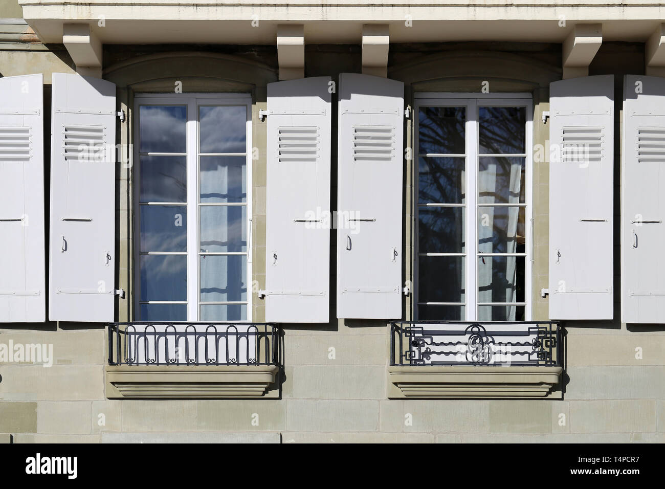 Details der alten mittelalterlichen Gebäude. Das Gebäude hat beige Betonwände und die Fensterrahmen sind weiß und aus Holz. In Nyon fotografiert. Stockfoto