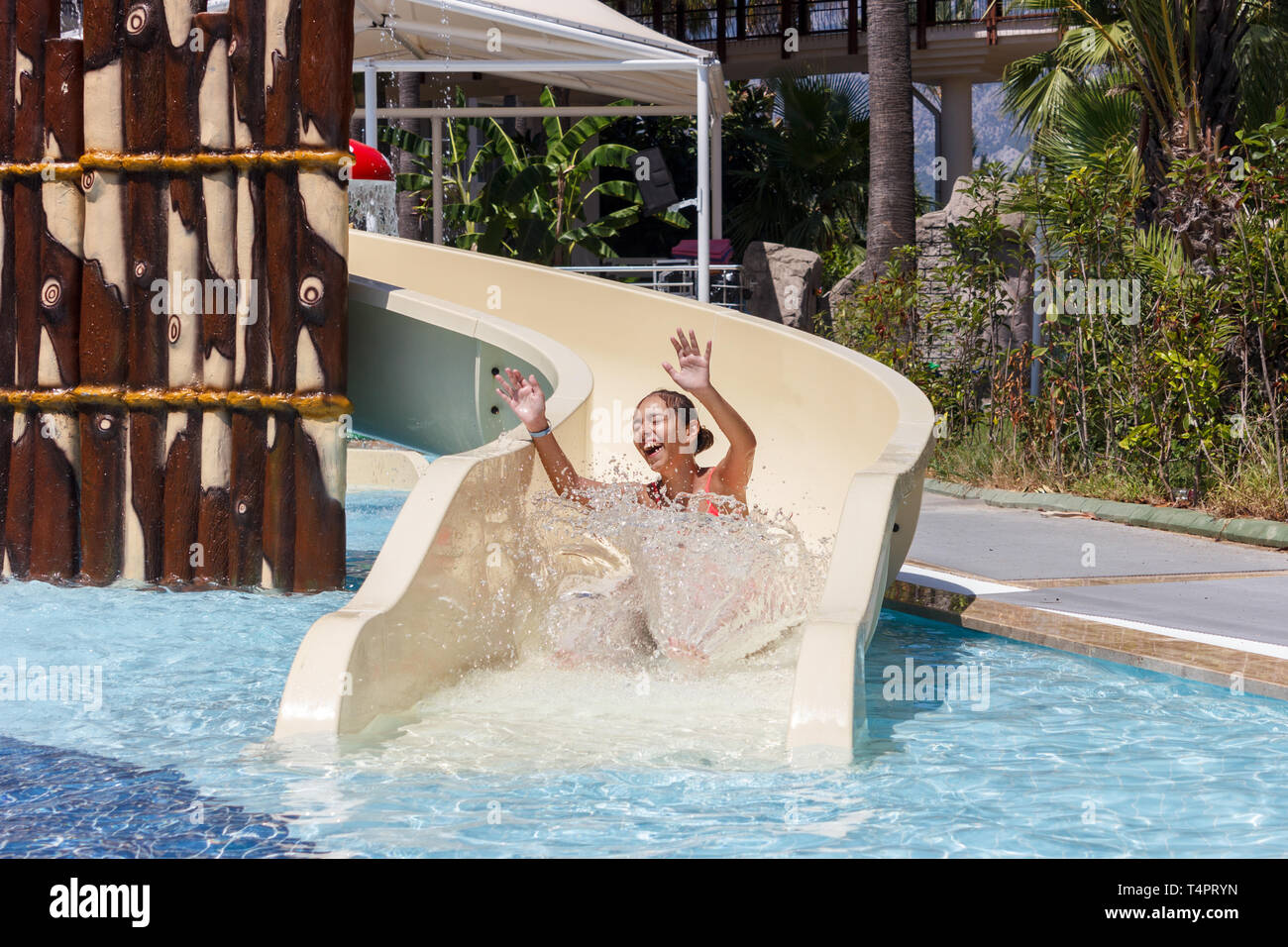Fröhlich lachend jugendlich Mädchen Dias aus der Wasserrutsche im Hotel Aquapark Stockfoto