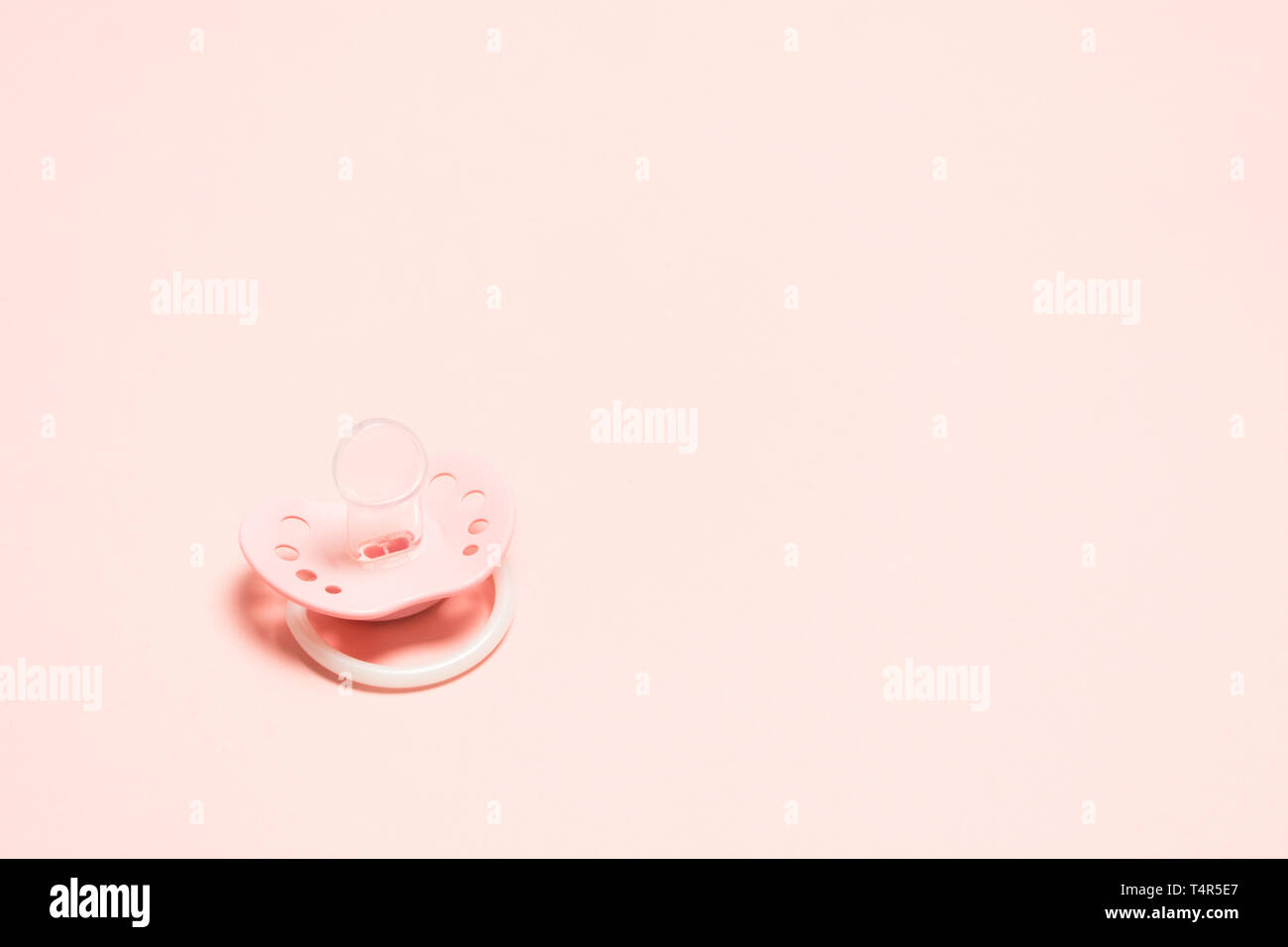 Rosa Silikon kieferorthopädische paifier mit Lüftungsschlitzen versehen, über rosa Hintergrund. Kindheit neborn Konzept. Baby girl Kunststoff Ausstattung entspannen. Kopieren Stockfoto