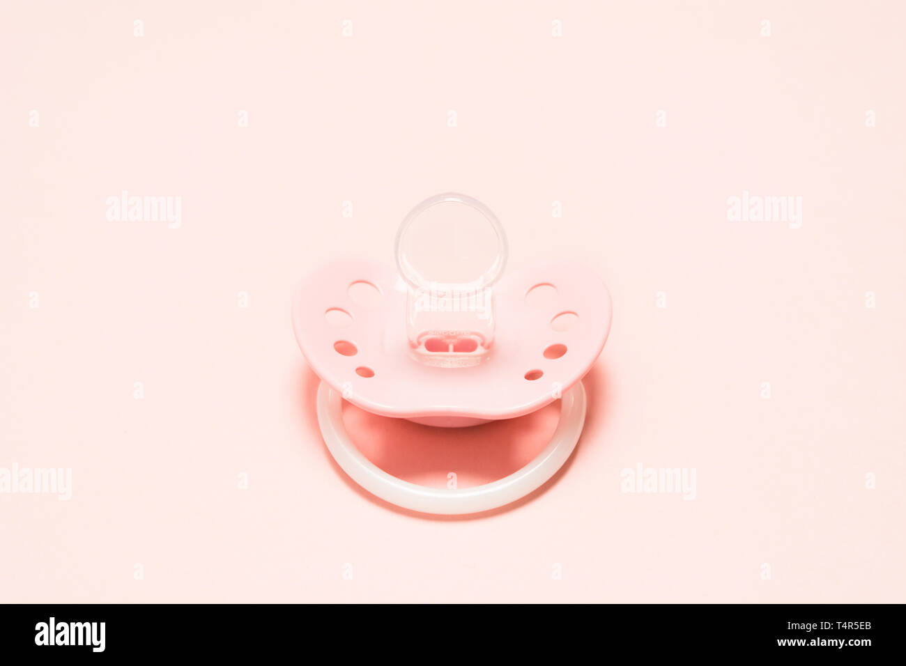 Baby Silikon kieferorthopädische paifier in rosa Farbe mit Lüftungsschlitzen versehen, über rosa Hintergrund. Kinder neugeborene Konzept. Baby girl Kunststoff equipme Entspannen Stockfoto