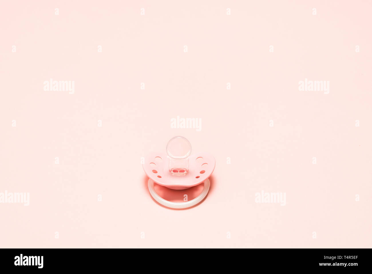 Silikon kieferorthopädische paifier mit Belüftungslöchern für Neugeborene über rosa Hintergrund. Kinder neugeborene Konzept. Baby girl Kunststoff Ausstattung Entspannen Stockfoto