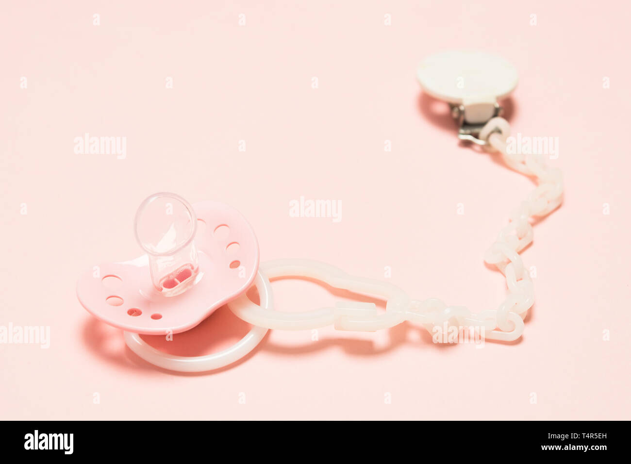 Rosa Silikon kieferorthopädische paifier mit Kunststoffhalterung über rosa Hintergrund. Kinder neugeborene Konzept. Baby girl Kunststoff Ausstattung entspannen. Mockup Stockfoto