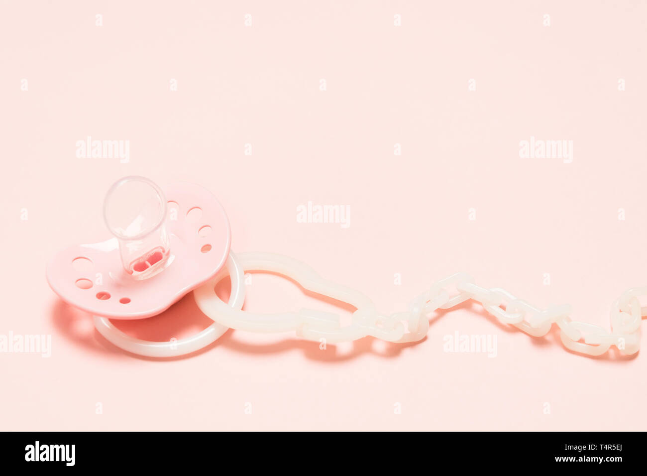 Baby Silikon kieferorthopädische paifier in rosa Farbe mit Belüftungsöffnungen mit Kunststoffhalter über rosa Hintergrund. Kindheit. Neugeborene Konzept. Baby Plas Stockfoto