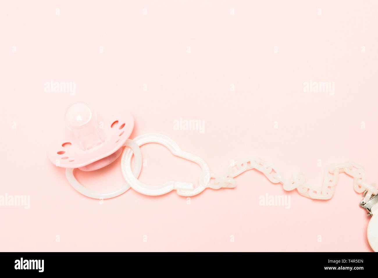 Rosa Silikon kieferorthopädische paifier mit Halter über rosa Hintergrund. Kinder neugeborene Konzept. Baby girl Kunststoff Ausstattung entspannen. Kopieren Sie Platz. Flach Stockfoto