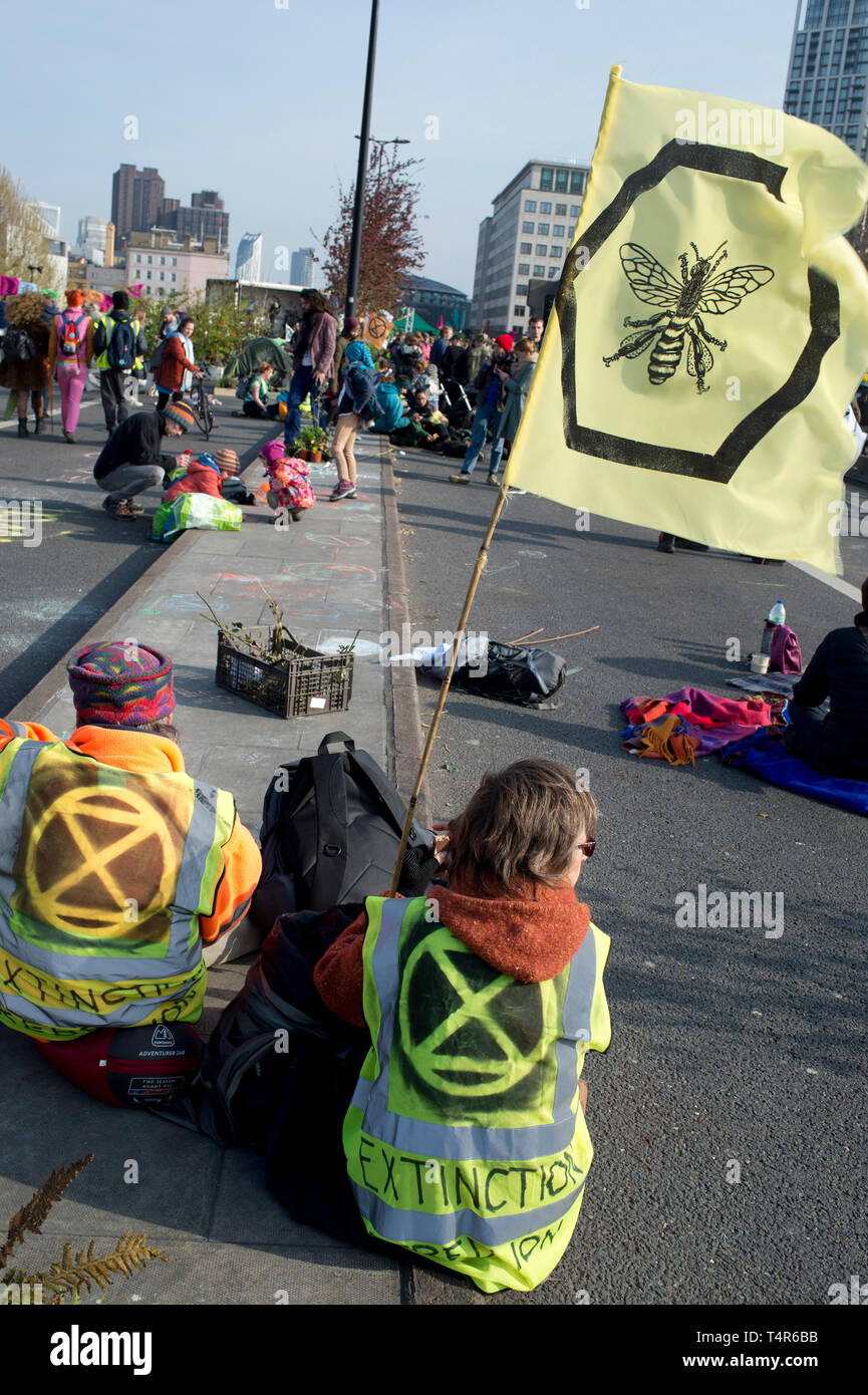 London 15 April 2019. Aussterben Rebellion Protest zu Maßnahmen gegen den Klimawandel verlangen. Waterloo Bridge; Demonstranten Sitzen mit einer Biene Flagge. Stockfoto