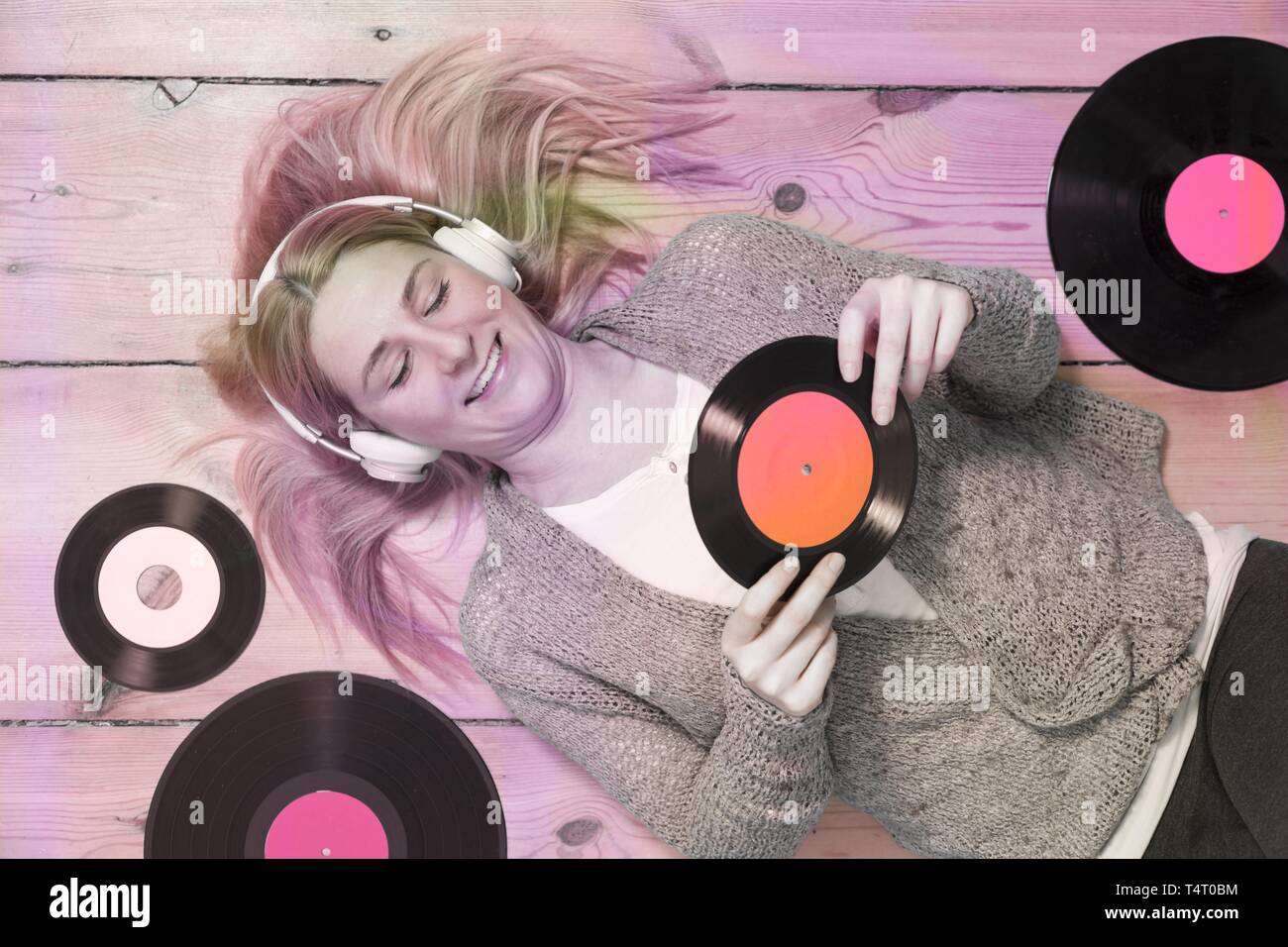 Junge blonde Frau liegend auf dem Holzboden, umgeben von Aufzeichnungen Stockfoto
