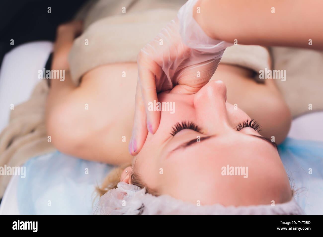 Kosmetiker macht eine bukkale Massage des Gesichts Die Muskeln des Patienten Stockfoto