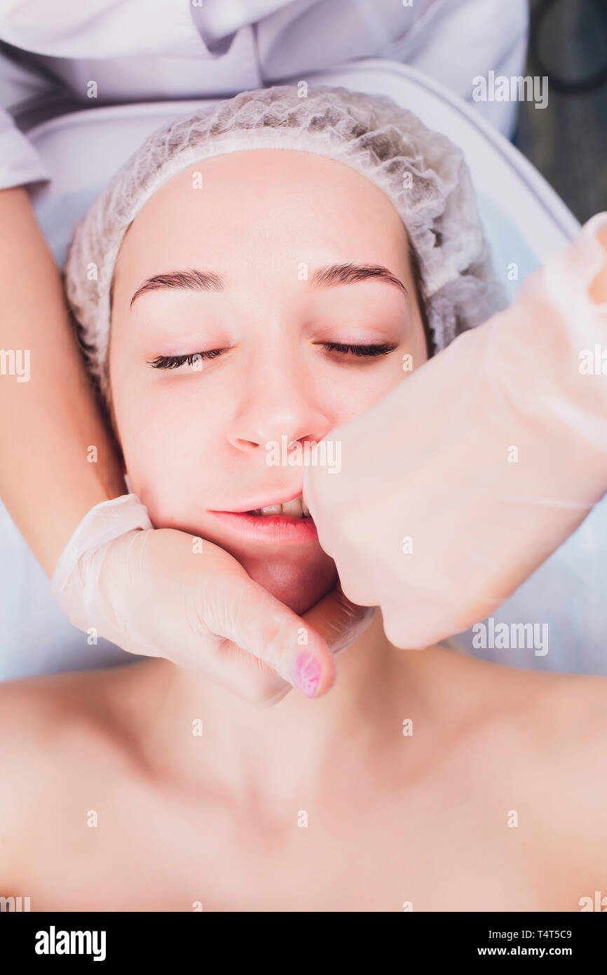 Kosmetiker macht eine bukkale Massage des Gesichts Die Muskeln des Patienten Stockfoto