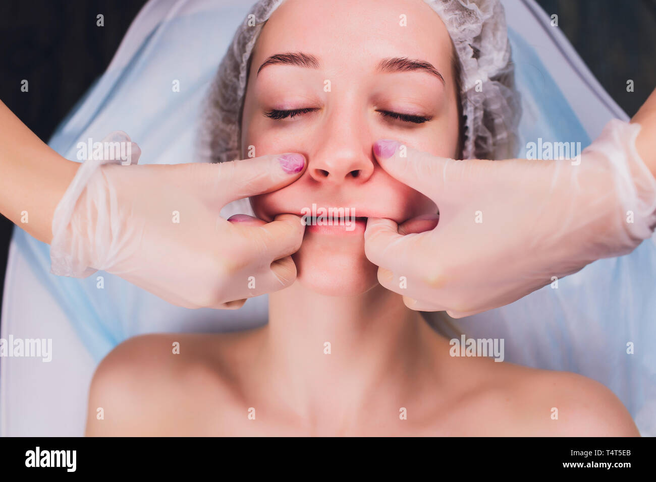 Kosmetiker macht eine bukkale Massage des Gesichts Die Muskeln des Patienten Stockfoto
