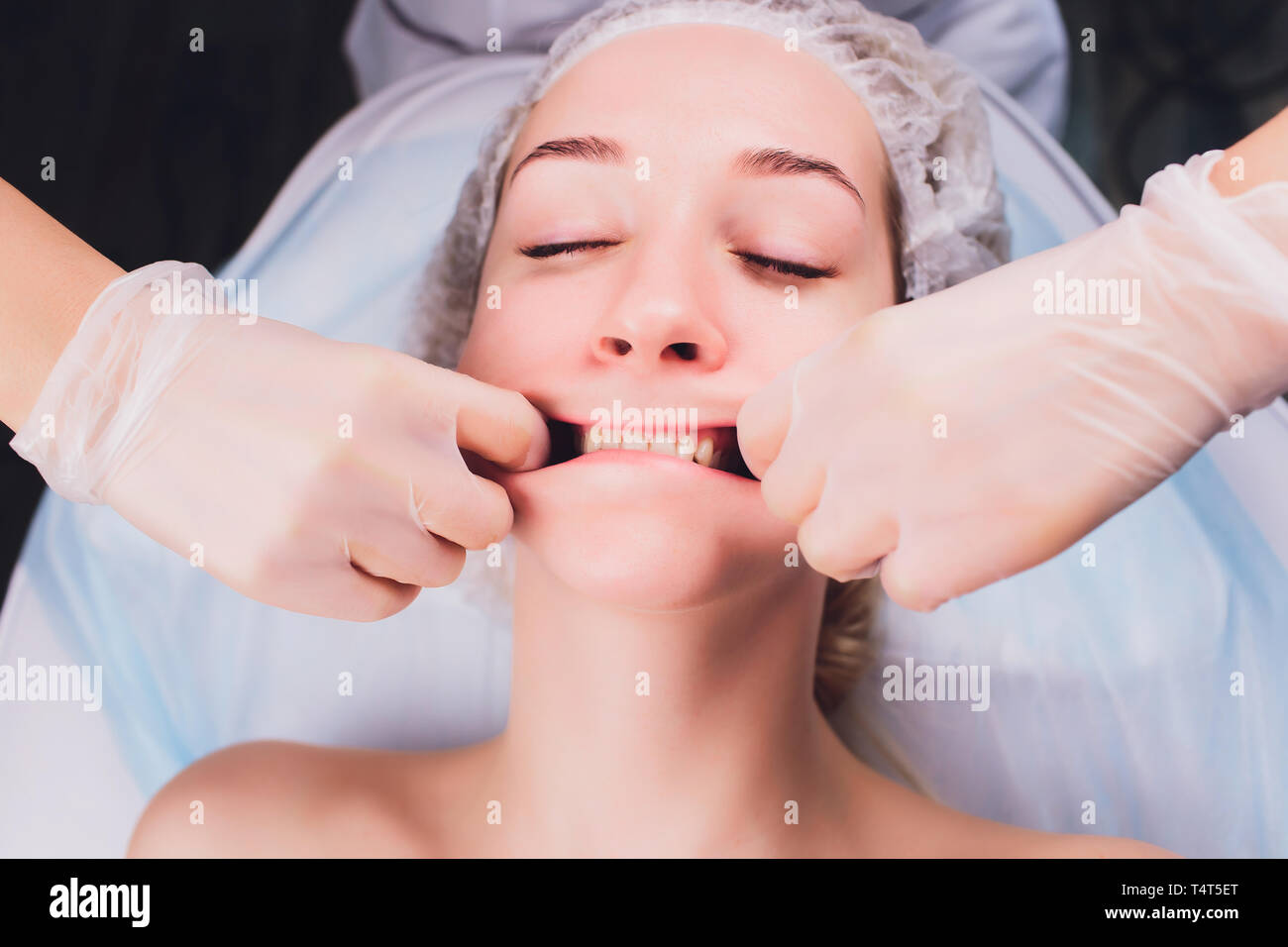 Kosmetiker macht eine bukkale Massage des Gesichts Die Muskeln des Patienten Stockfoto