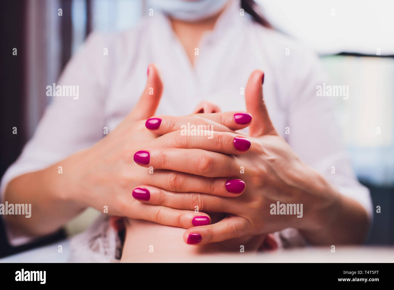 Kosmetiker macht eine bukkale Massage des Gesichts Die Muskeln des Patienten Stockfoto