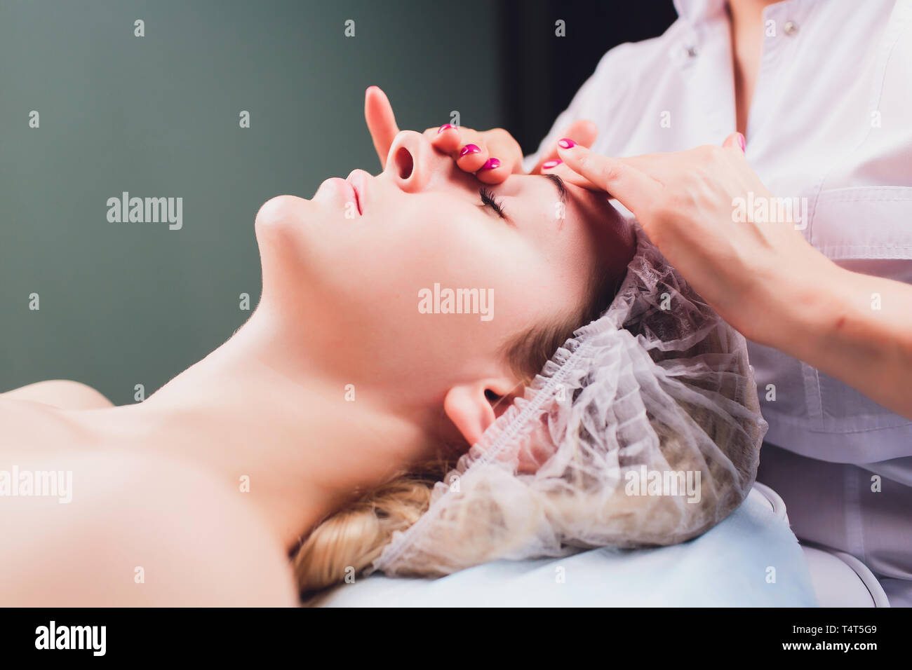 Kosmetiker macht eine bukkale Massage des Gesichts Die Muskeln des Patienten Stockfoto