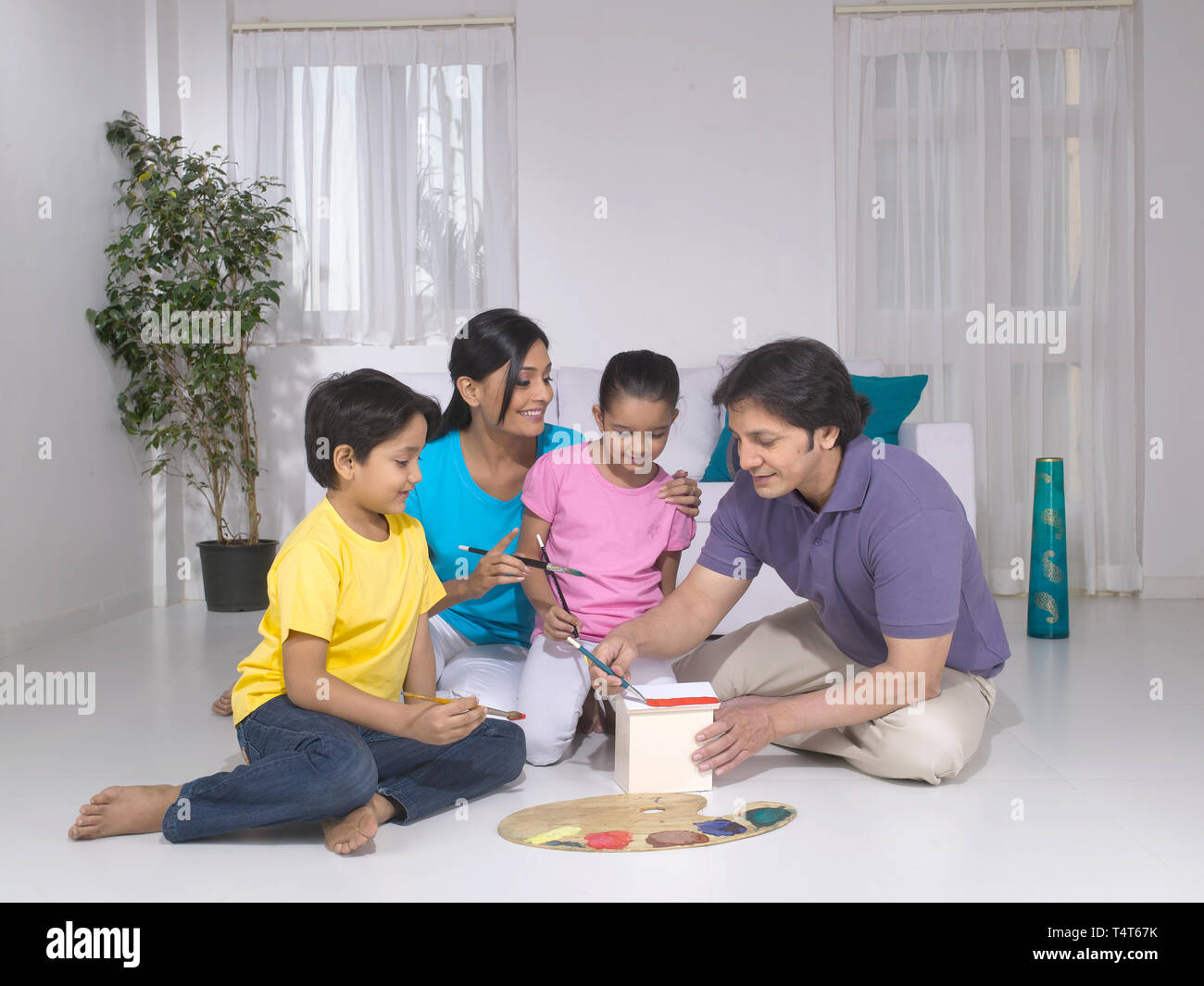 Indische FAMILIE VON 4 Malerei ein Spielzeug HAUS IN IHREM HAUS Stockfoto