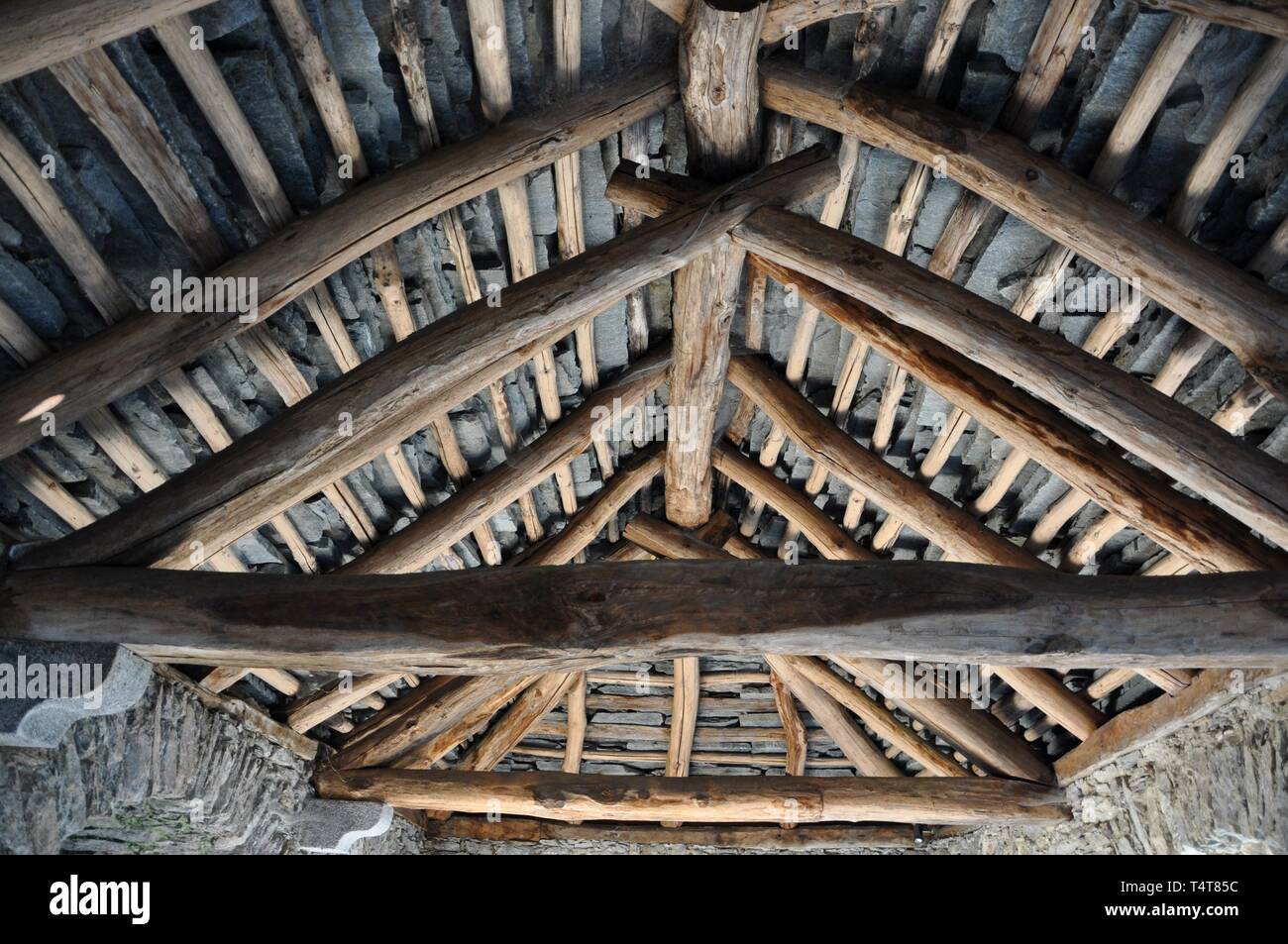 Alte urige Hütte mit Stein Dach und Holzbalken von drinnen in der Schweiz Stockfoto