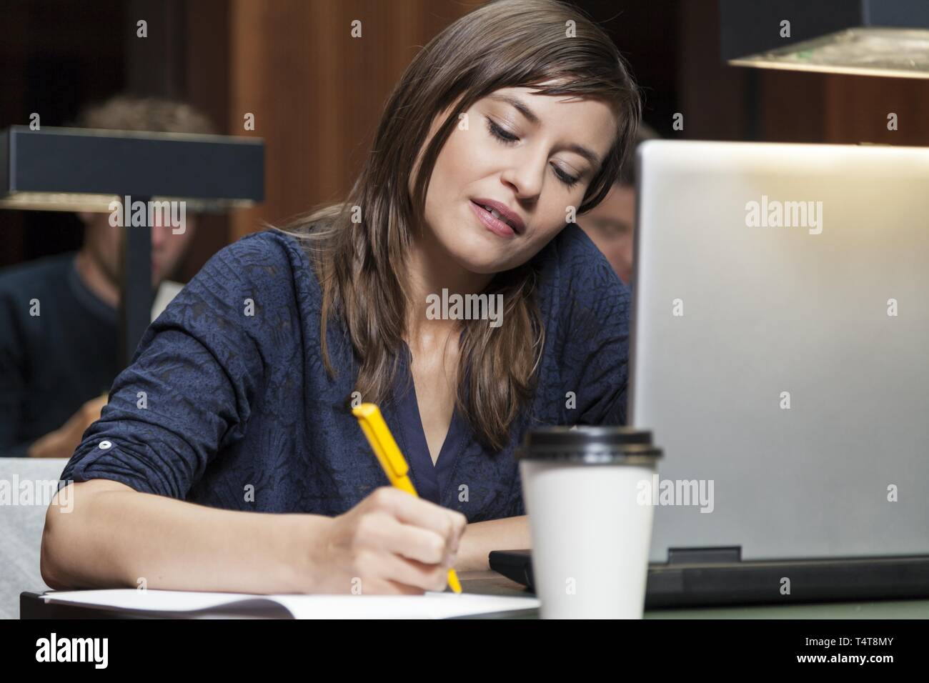 Schüler Schreiben mit einem Stift in der Bibliothek Stockfoto