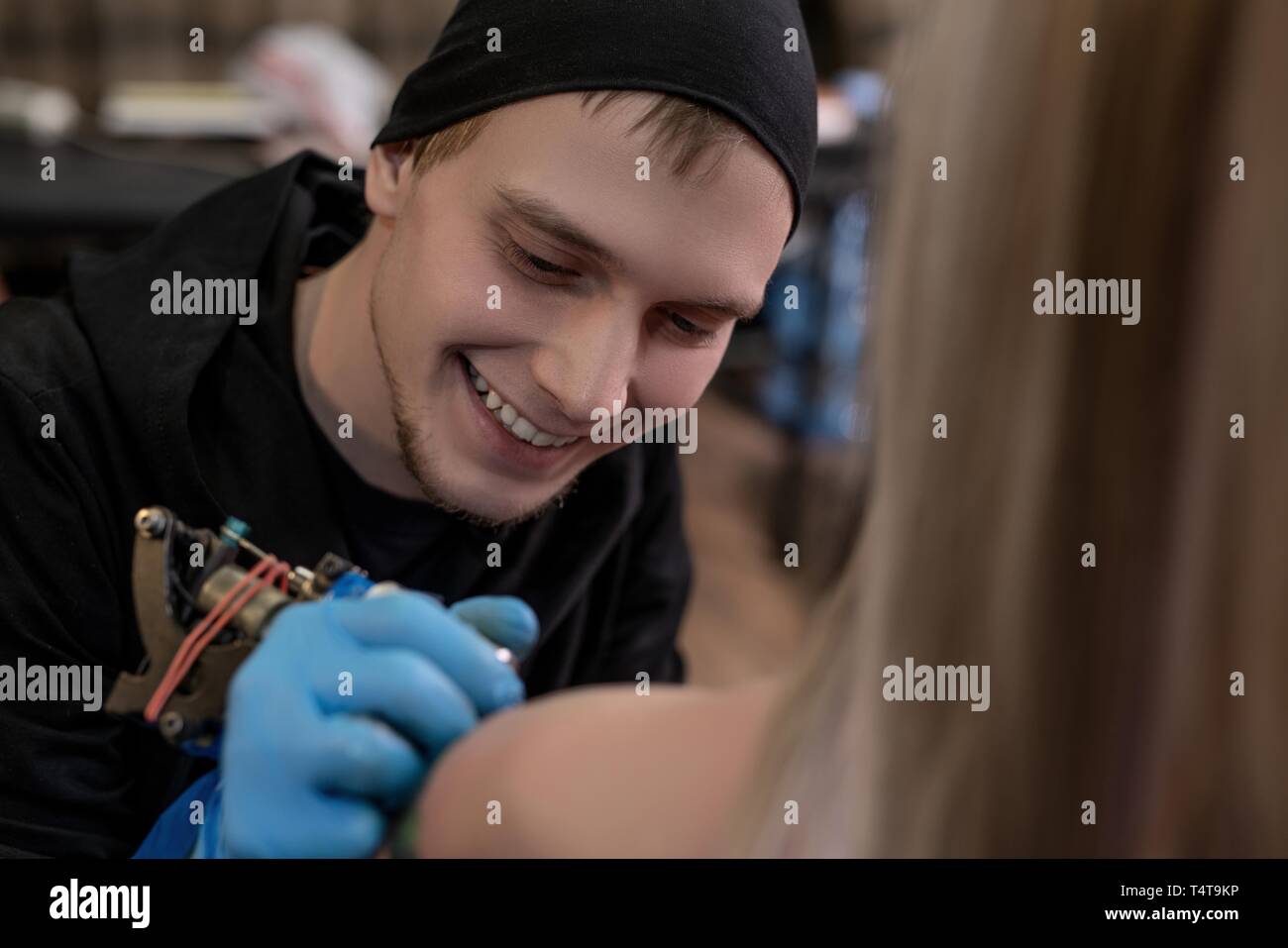 Glücklicher Tätowierer mit Instrument bei Arbeitsaufnahme Stockfoto