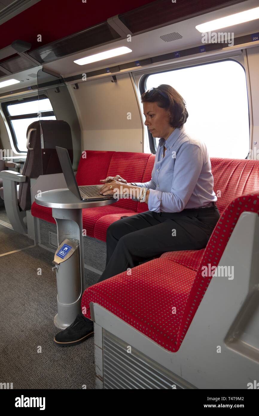 Business Woman in der ersten Klasse der Bahn sitzend, Arbeiten mit Laptop und Mobiltelefon, Schweiz Stockfoto