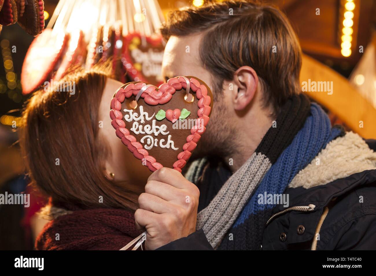 Ein paar Küssen hinter einem Lebkuchenherz, Lebkuchen Herz mit sagt 'Ich liebe dich', der Weihnachtsmarkt, Deutschland, Europa Stockfoto