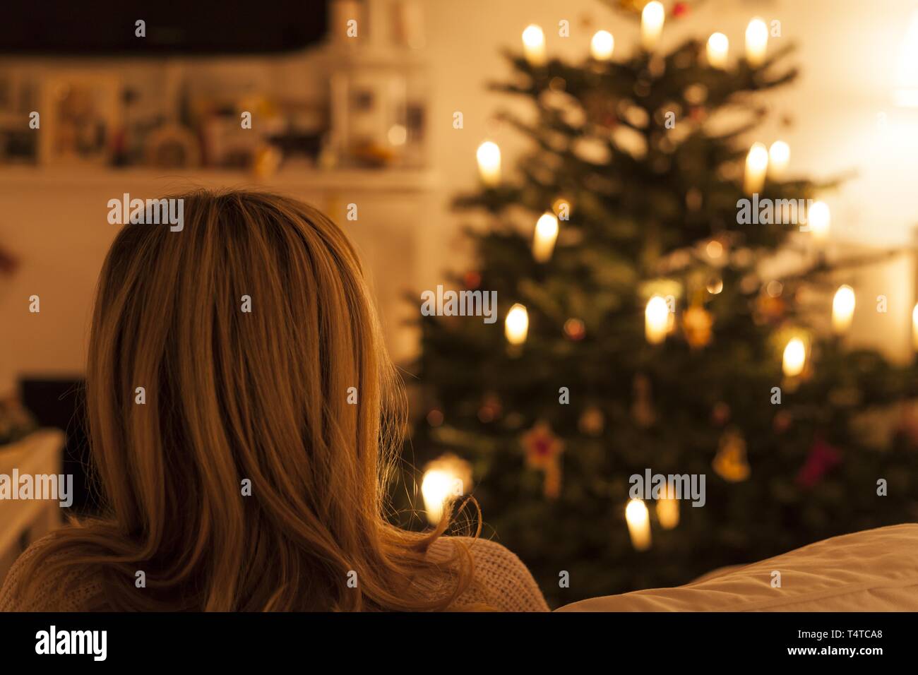 Frau sitzt auf einem Sofa vor dem Weihnachtsbaum ist, Rückansicht Stockfoto