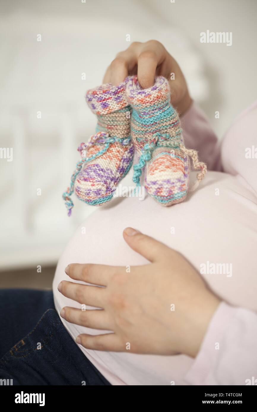 Schwangere Frau mit gestrickten Socken auf baby Bauch Stockfoto