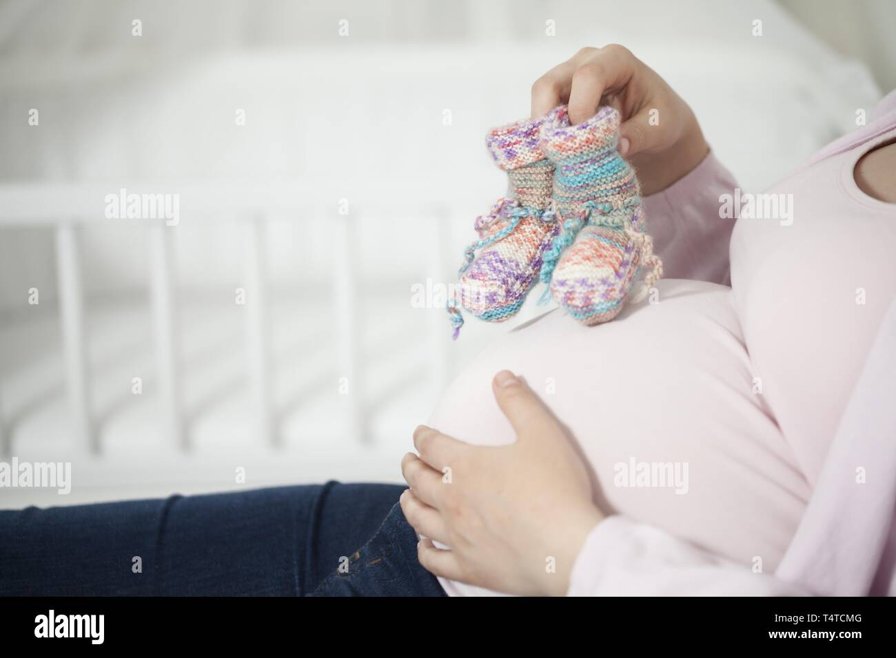 Schwangere Frau mit gestrickten Socken auf baby Bauch Stockfoto