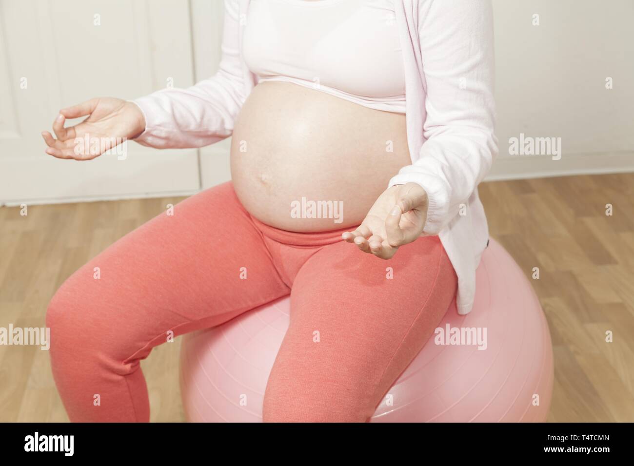 Schwangere Frau sitzt auf einer übung Kugel und meditieren Stockfoto