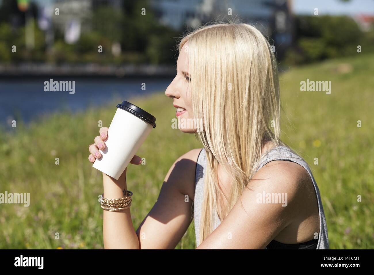 Jugendlich imit Tasse Kaffee auf einer Wiese Stockfoto