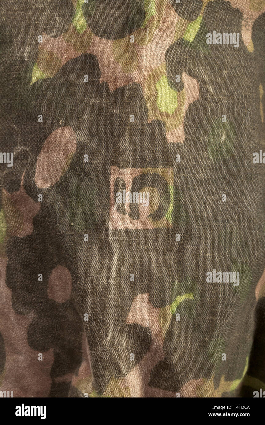 Ein LACE-up Shirt M 42, 2. Typ reversible Design in Platane Muster aus reversible Zeltstoffen, im Frühjahr und Herbst Farben gedruckt, mit gleichen Verschraubungen auf beiden Seiten: Verstärkter öse Knopfleiste auf der oberen Hälfte der fünf Öse Paare mit einer Öse Knopfloch Nähmaschine umrandet. Schräg (die 1. Ausgabe gerade) Gesäßtaschen mit Tasche die Beläge der sandfarbene Bettwäsche, die oberen Klappen befestigt mit kugelförmigen Tasten bekannt als Napfknöpfe. Mehrere Sätze von drei Befestigung loops Jede Aufgenäht auf dem oberen Körper, für Camouflage Material. Elastische Bänder eingefügt nur unten, Editorial-Use - Nur Stockfoto