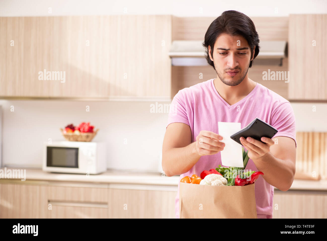 Junger stattlicher Mann mit Gemüse in der Küche Stockfoto