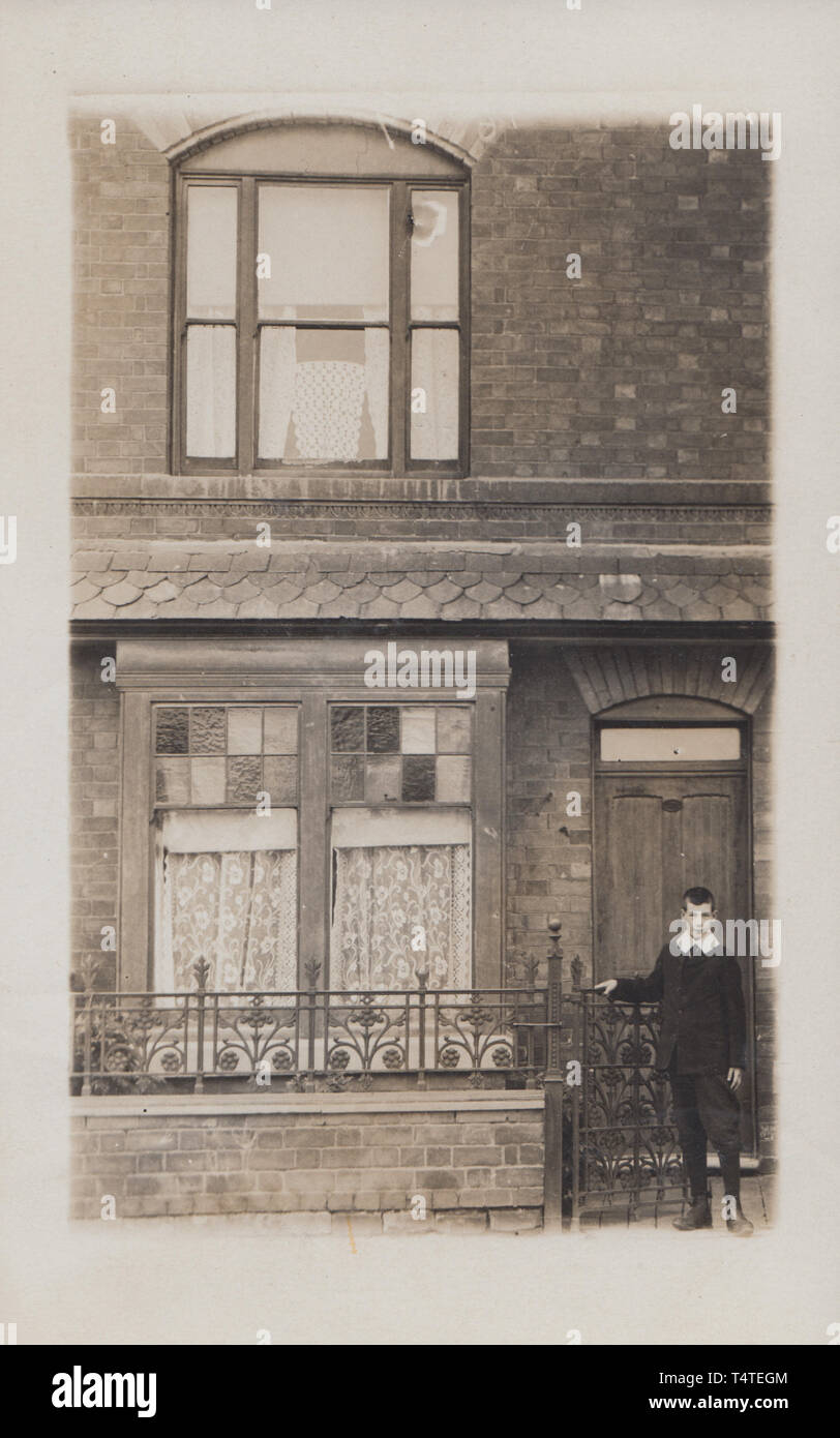 Jahrgang fotografische Postkarte zeigt einen historischen britischen Heimat mit einem edwardianischen Junge stand auf der Vorderseite Tor. Stockfoto