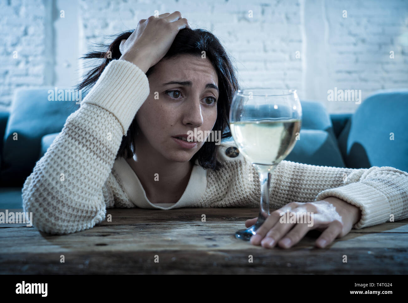 Betont und hoffnungslose junge Frau trinkt ein Glas Wein allein zu Hause. Deprimiert, frustriert und schwach, versuchen, besser trinken zu fühlen. Unhe Stockfoto