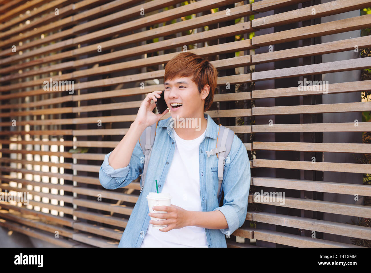 Junge asiatischer Mann lächelnd und Gespräch am Handy außen mit Kopie Raum auf der linken Seite Stockfoto