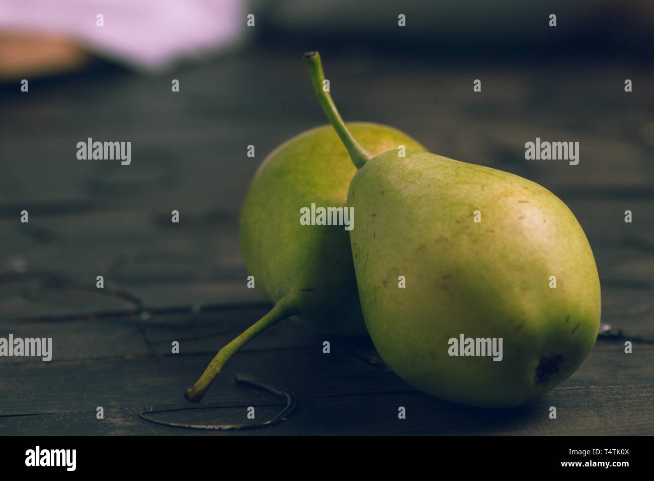 Birnen zu essen mit einem hölzernen Messer und auf braunem Hintergrund ausschneiden Stockfoto