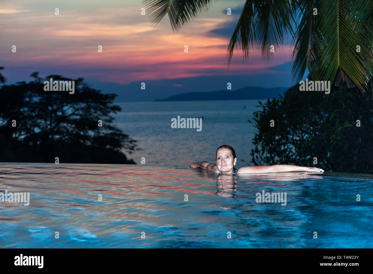 Eine Frau, die am Rande der einen Pool mit Meerblick Stockfoto