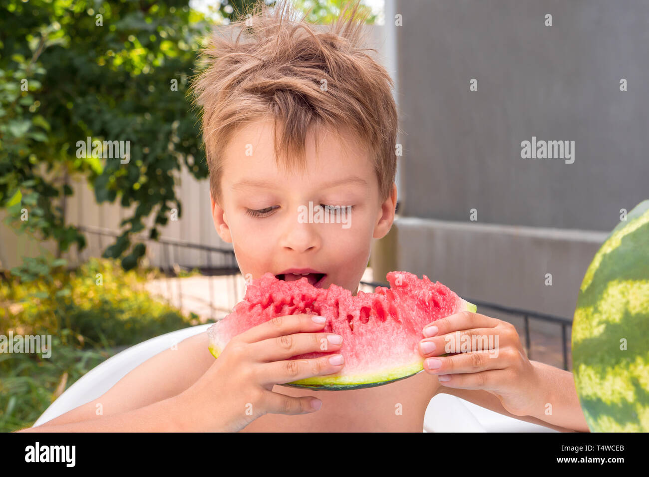 Glückliche Kindheit Konzept. Sommerferien Hintergrund. Schulferien Konzept. Junge, Essen, Wassermelone, draußen im Garten, front, Hinterhof. Reife Stockfoto