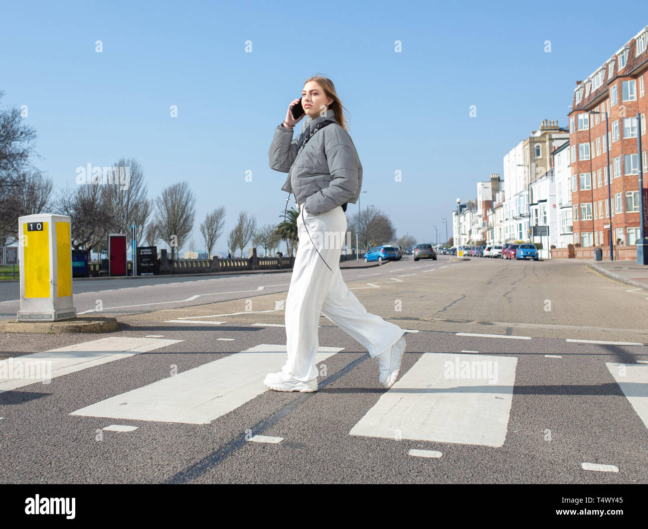 Junges Mädchen gehen über einen Zebrastreifen auf Ihrem Mobiltelefon Stockfoto