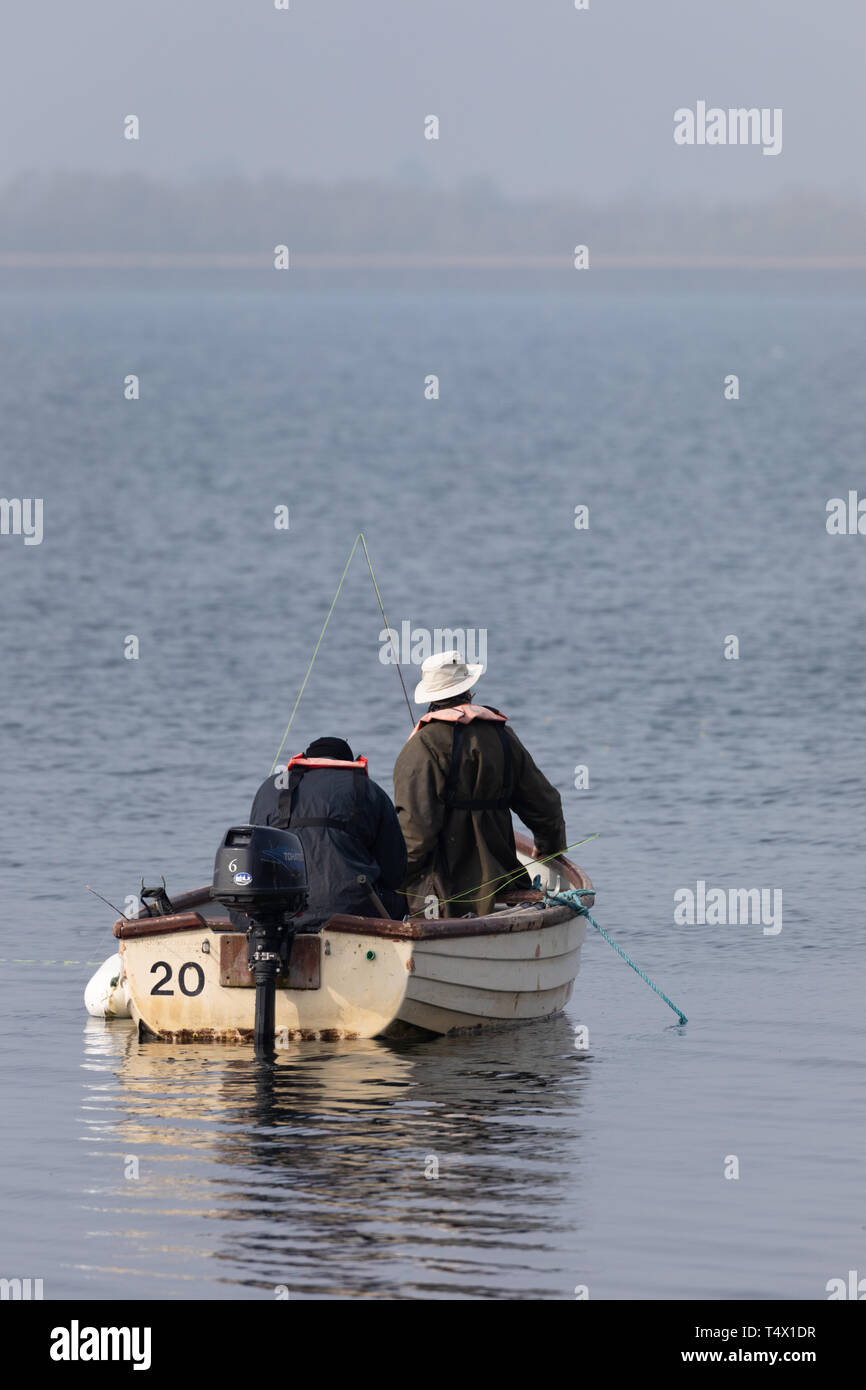 Rugby, Warwickshire, UK - 18. April 2019: Zwei Angler in einem kleinen Boot mit Aussenbordmotor flott auf dem Wasser von einem Behälter. Stockfoto