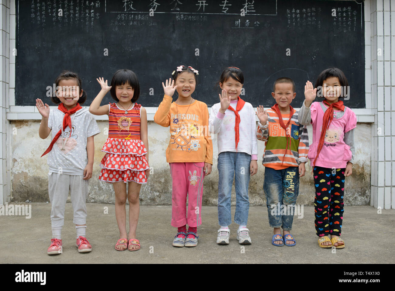Primäre alter Schule Kinder Leitung für ein Foto in der Schule Spielplatz und Wave. Ländliche Region Guangxi, Südchina. Stockfoto