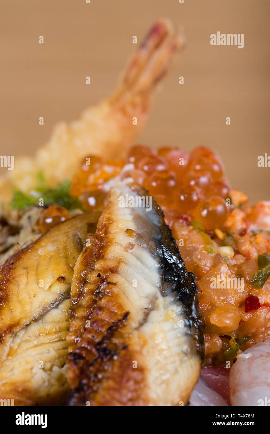 Typische japanische Fisch donburi, Shrimp Tempura, rohe Garnelen, Lachs Filets, gegrillter Thunfisch, Kaviar, Thunfisch Tartar, in Scheiben geschnittene Gurken, raw Wolfsbarsch Fischfilets Stockfoto