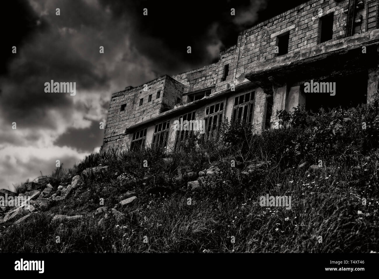 The Haunted House. Ein verlassenes Geisterhaus, in Schwarz und Weiß auf einem Hügel in der Nacht. Stockfoto