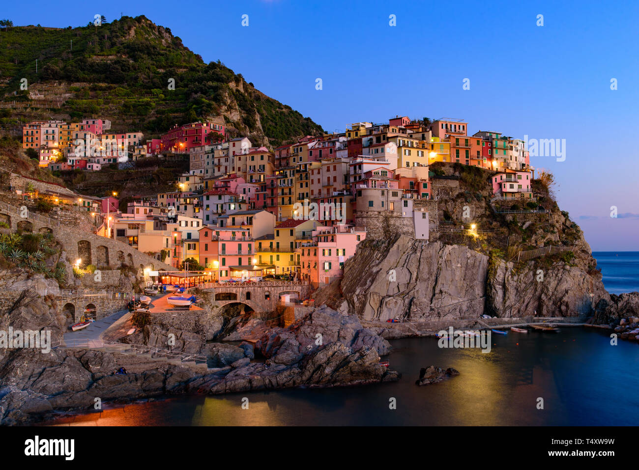 Sonnenuntergang und Nacht Blick über Manarola, einer der fünf mediterranen Dörfer der Cinque Terre, Italien, bekannt für seine bunten Häuser und den Hafen. Stockfoto