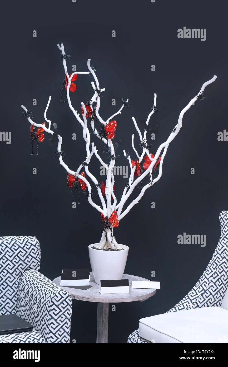 Dekorative weiße Baum im Blumentopf mit roten Schmetterlinge auf einem kleinen Tisch Stockfoto