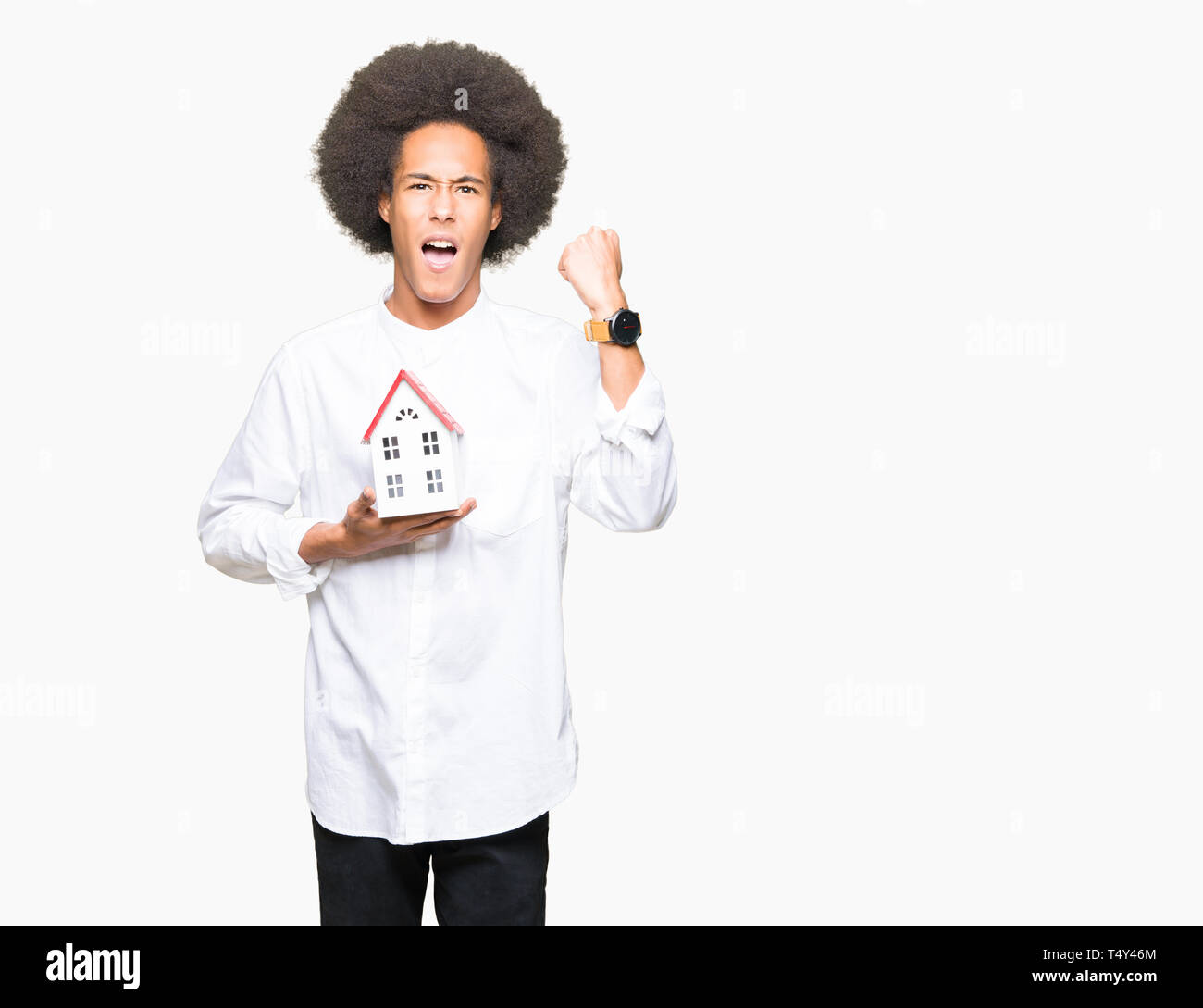 Junge afrikanische amerikanische Mann mit afro Haar holding Haus genervt und frustriert schrie mit Zorn, verrückt und schreien mit erhobener Hand, Wut Konzept Stockfoto