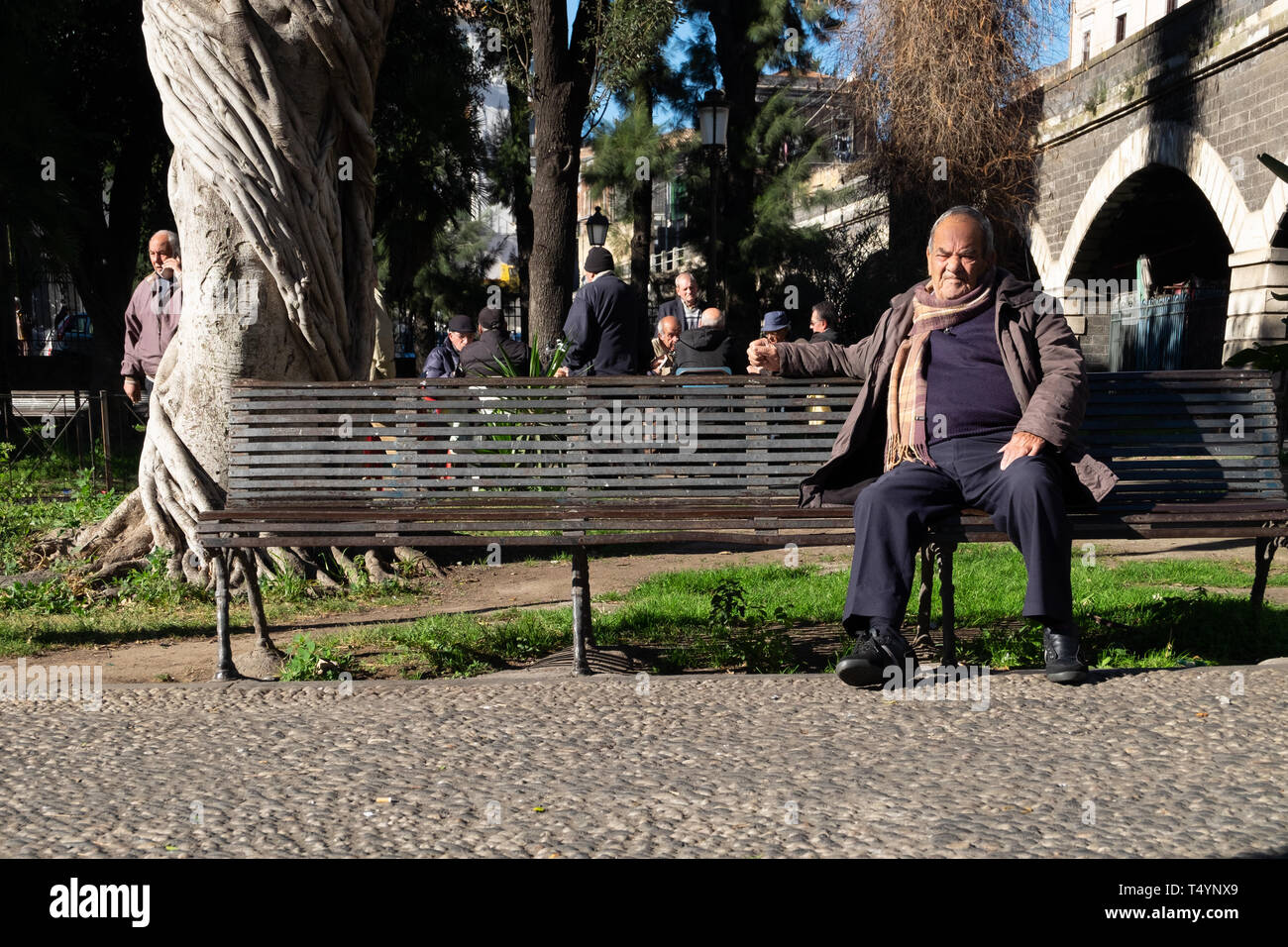 Sizilien, Italien - Januar 21, 2016: Unbekannter alter Mann zitiert, die auf einer Bank sitzen auf lokaler Park am Vormittag in Catania. Stockfoto