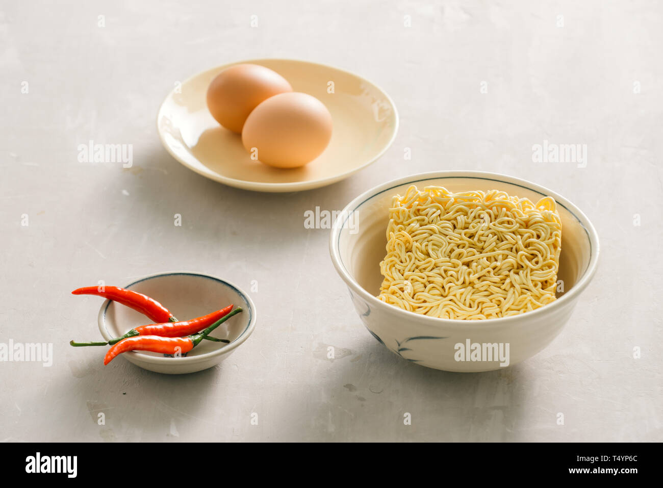 Instant Nudeln in der Schüssel und Gemüsebeilagen auf Stein Hintergrund. Schnell & einfach essen Konzept. Stockfoto