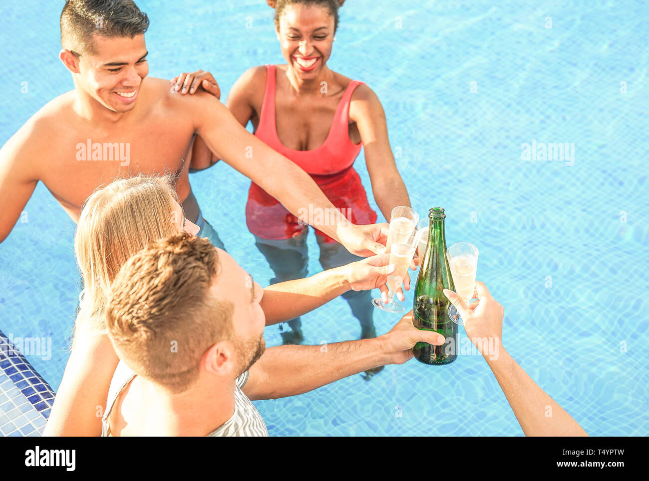Gerne Freunde jubeln mit Champagner in den Pool - den Jugendlichen Spaß macht eine Partei und toasten Gläser Prosecco Stockfoto