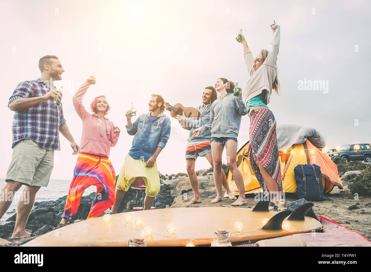 Gerne Freunde tanzen und Spaß haben, eine Beach Party auf dem Campingplatz - Junge Menschen lachen und trinken Bier beim Camping nächsten Ozean Stockfoto