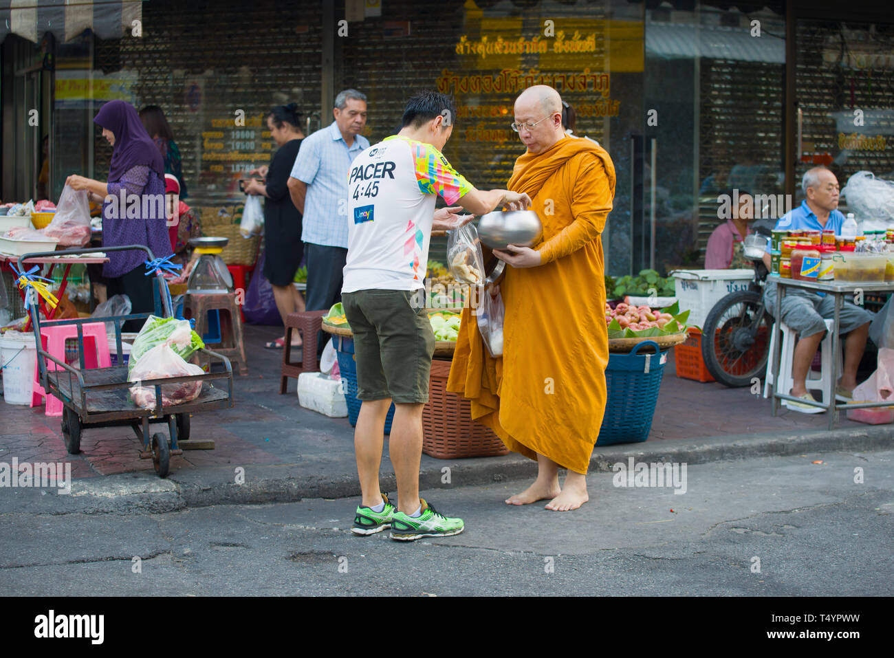 BANGKOK, THAILAND - 27. Dezember 2018: Ein buddhistischer Mönch sammelt Lebensmittel auf einer Straße der Stadt Stockfoto