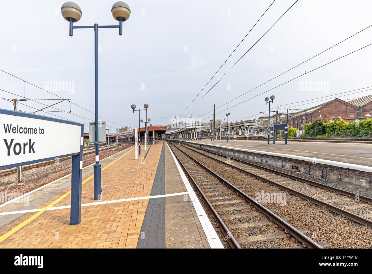 Der Bahnhof York mit Plattformen und Schienen, die nach innen. Eine Station Ort Zeichen im Vordergrund steht und ein blauer Himmel ist oben. Stockfoto