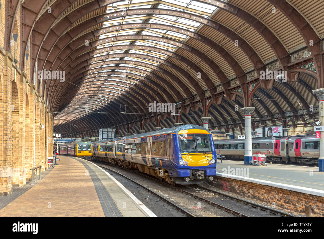 Der Bahnhof York mit Plattformen und Schienen, die nach innen. Zwei Züge warten unter einem 19. Jahrhundert Metall und Glas gebogene Vordach. Stockfoto